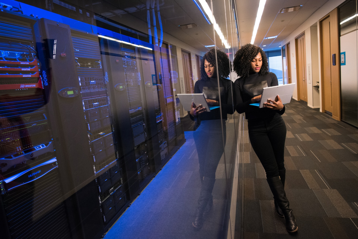 Women standing with a laptop next to a room full of computers